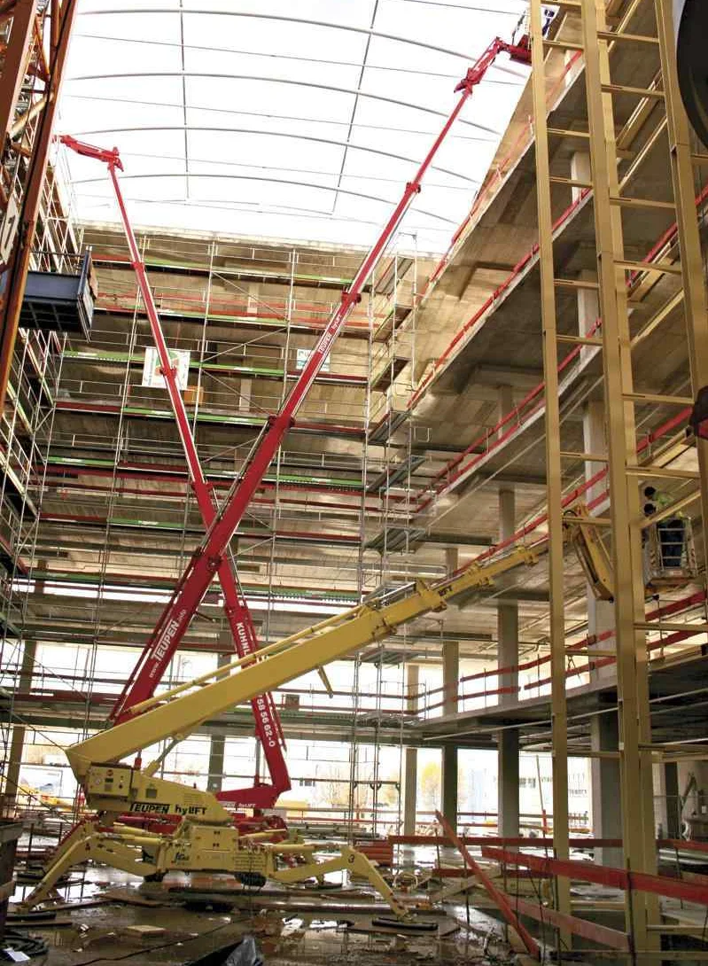 Ausgefahrene Arbeitsbühnen in verschiedenen Farben in einem unvollendeten Gebäude.