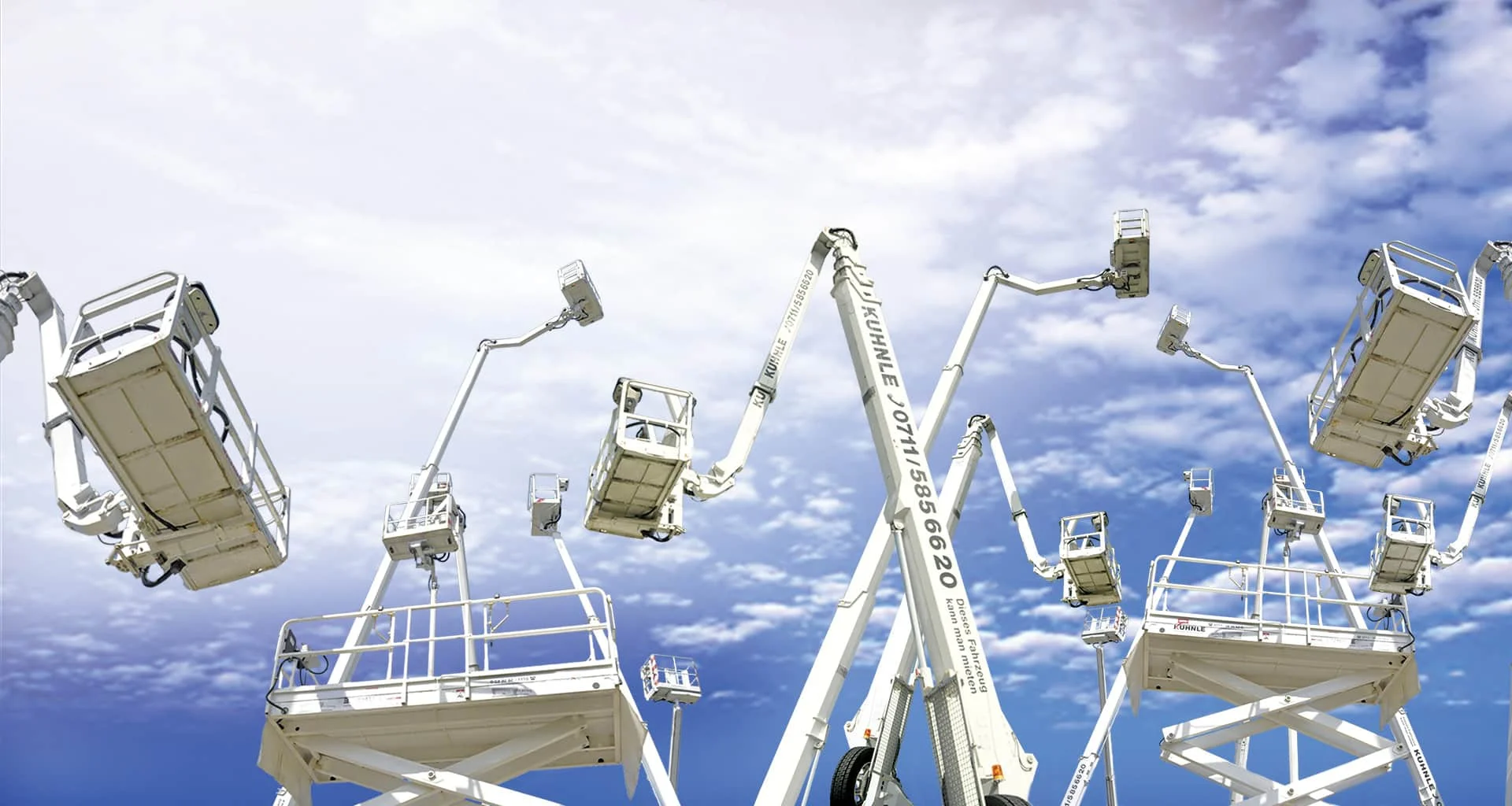 Gruppe von Arbeitsbühnen in ausgefahrenem Zustand vor wolkigem blauen Himmel.