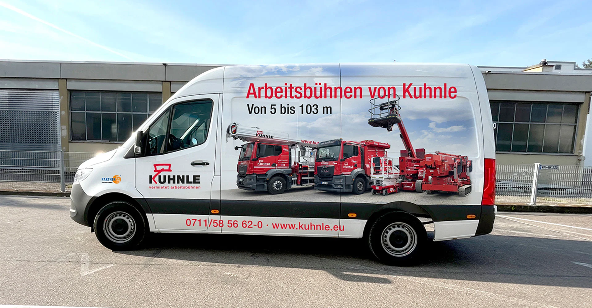 Seitliche Ansicht eines Vans mit Aufdruck von drei nebeneinander geparkten roten Arbeitsbühnen.