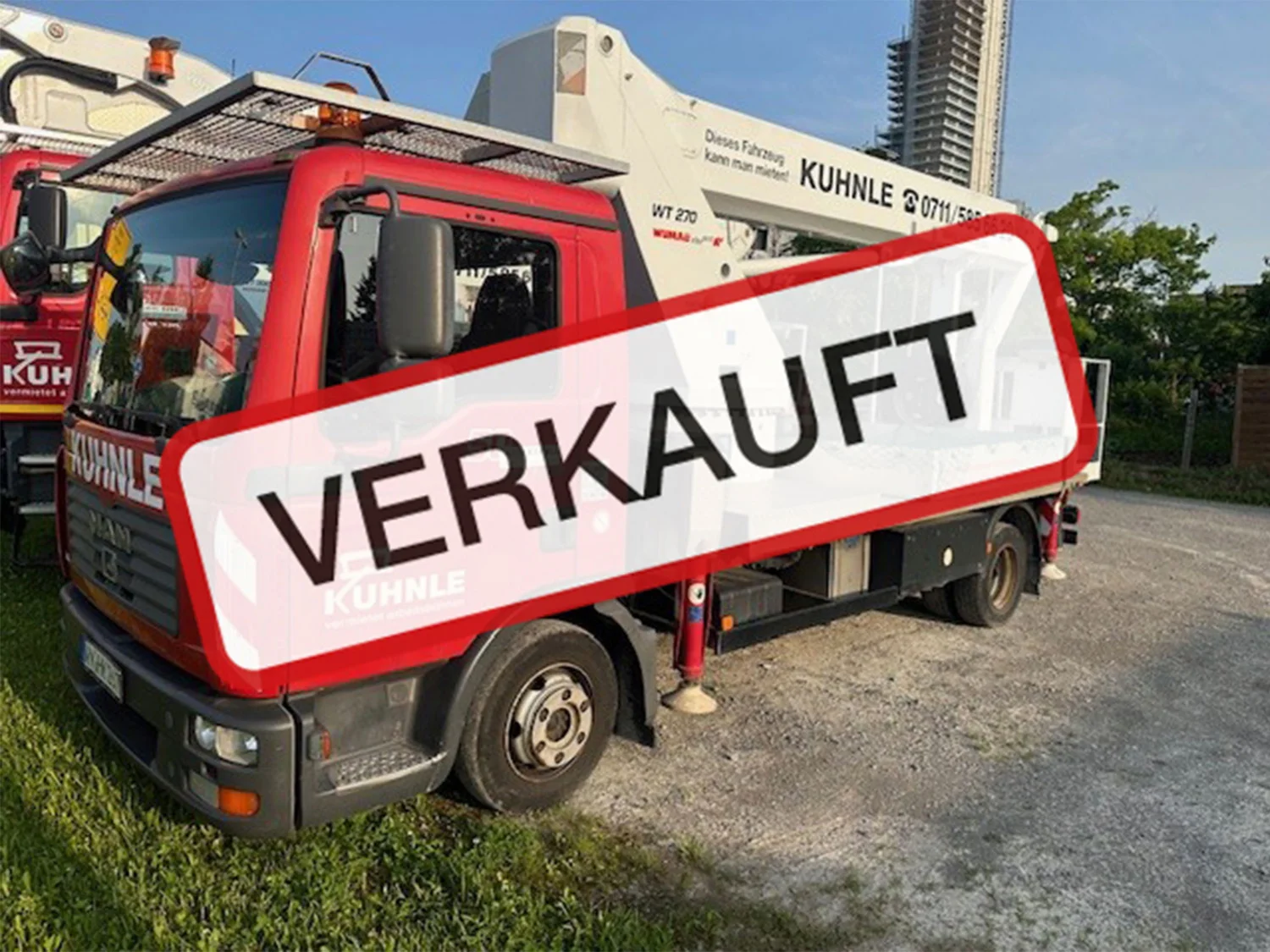 Arbeitsbühne teils auf Wiese und Straße geparkt, "Verkauft"-Text darüber.