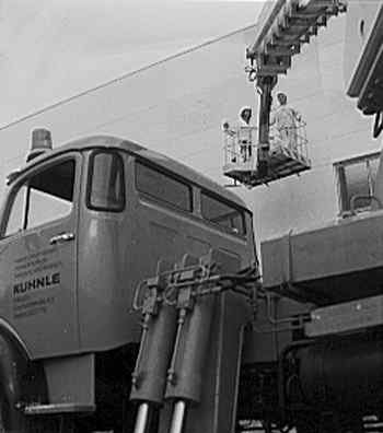 Historisches Schwarzweißfoto: Arbeitsbühne mit Personen darauf im Hintergrund